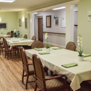 A neatly arranged dining area with tables and chairs, complemented by potted plants.