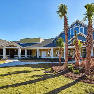 A beautiful house with palm trees and well-maintained landscaping under a clear blue sky.