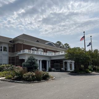 A well-designed building with flags in front under a cloudy sky.