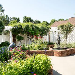 A serene garden featuring vibrant flowers, a tranquil fountain, and a charming sculpture amidst lush greenery.