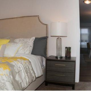 A cozy bedroom with a neatly made bed and a stylish nightstand featuring a lamp.