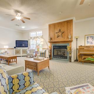 A cozy and spacious living room featuring a fireplace, television, piano, and comfortable seating arrangements.
