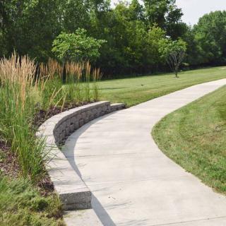 A curved concrete pathway surrounded by greenery in a park setting.