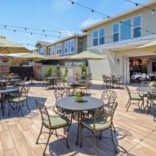 A sunny outdoor patio with tables, chairs, and string lights.