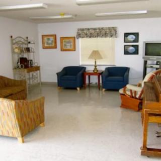 A cozy living room with various furniture items including sofas, chairs, a piano, and a television.