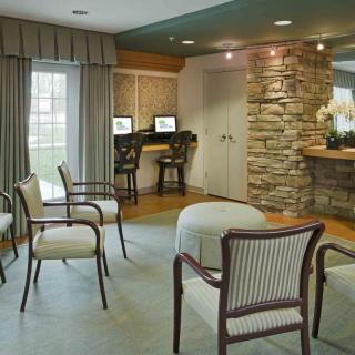 A cozy waiting area with seating, computers, and a stone-accented wall.