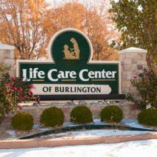 Sign for Life Care Center of Burlington with autumn foliage in the background.