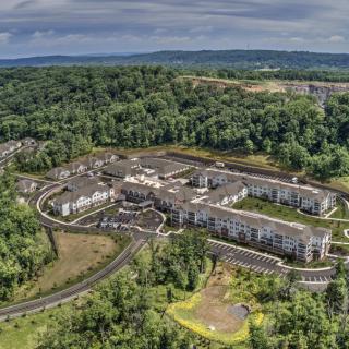 Aerial view of a large building complex surrounded by dense forest and greenery.