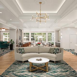 A stylish and modern living room featuring a cozy sofa, elegant chandelier, and ample natural light.