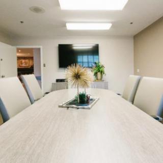 A modern conference room with a large table, comfortable chairs, and a television on the wall.