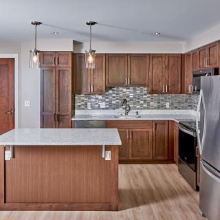 A modern kitchen with wooden cabinets, featuring an island and stainless steel appliances.