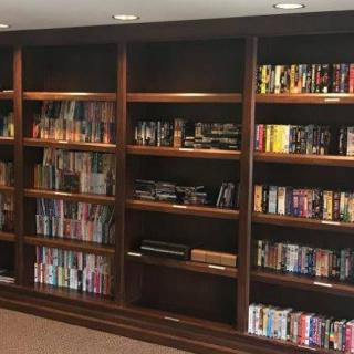 A spacious wooden bookshelf filled with a variety of books and media.