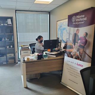 An employee working at their desk in an office, with a promotional banner in the background.