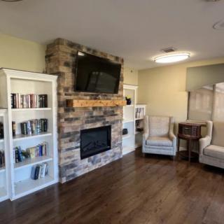A cozy living room with a fireplace, bookshelves filled with books, and comfortable seating.