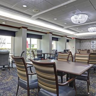 A spacious dining area with tables and chairs, featuring large windows and elegant lighting.
