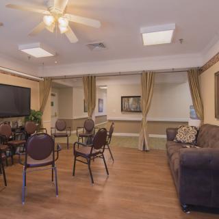A cozy living room with seating area, featuring a couch, chairs, a table, and a television.