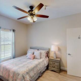 A cozy bedroom featuring a bed with patterned bedding, a nightstand with a lamp, and a ceiling fan.