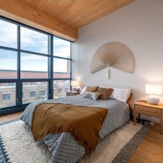A modern bedroom with large windows, natural light, and stylish decor.