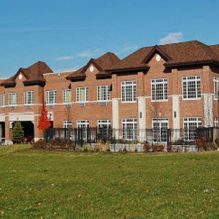 A modern brick building surrounded by green grass under a clear blue sky.