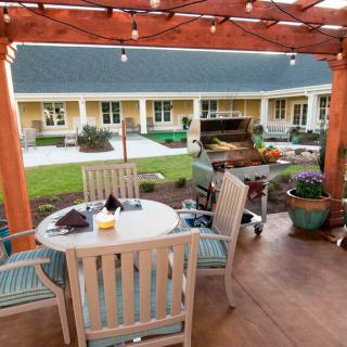A cozy outdoor patio area with a pergola, featuring seating and a garden view.
