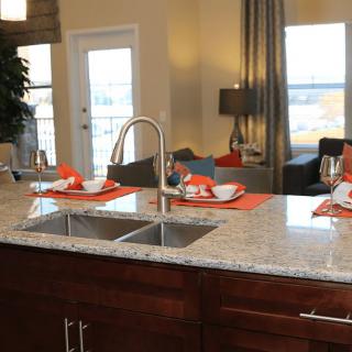 A modern kitchen with a granite countertop and elegant place settings.