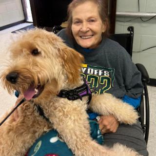 A joyful moment shared between a woman in a wheelchair and her therapy dog, showcasing the bond of companionship.