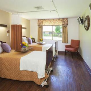 A well-equipped patient room featuring two beds, natural light, and comfortable furnishings.