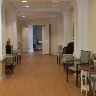A well-lit hallway with chairs and tables lined along the walls, featuring decorative elements.