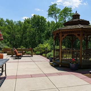 A sunny outdoor patio area with a gazebo and surrounding greenery.