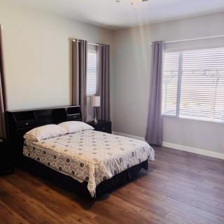 A simple bedroom with a bed, nightstand, and ample natural light.