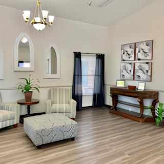 A cozy living room with elegant furnishings and decor, featuring a chandelier, wall art, and potted plants.