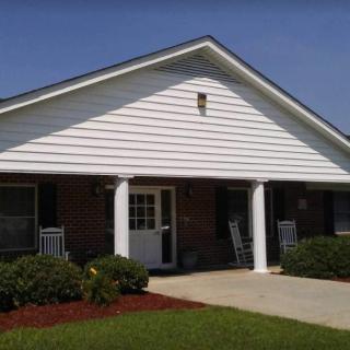 A small residential house with a porch and well-maintained lawn.