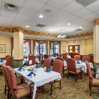 A well-decorated dining room with elegantly set tables and upholstered chairs.
