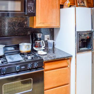 A cozy kitchen with a stove, oven, refrigerator, and coffee maker on the countertop.