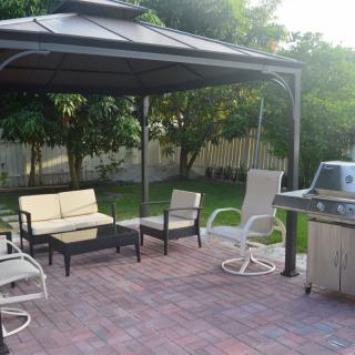 A cozy patio setup with a gazebo, seating area, and a grill for outdoor gatherings.