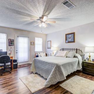A cozy bedroom featuring a neatly made bed, ceiling fan, and hardwood flooring.