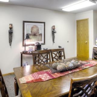 A well-furnished conference room with a long wooden table, chairs, and decorative artwork on the walls.