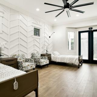 A modern bedroom featuring twin beds, a chevron-pattern accent wall, and sleek wood flooring.