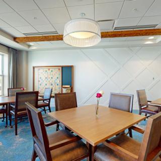 A modern dining room with a wooden table, chairs, and contemporary lighting.