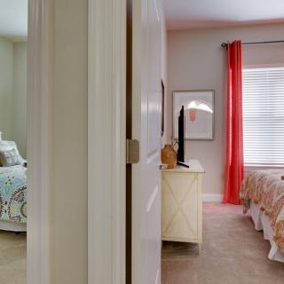 A view of two adjoining bedrooms with stylish furniture and decor.