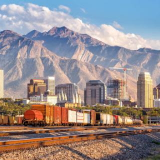 A scenic view of a city skyline with mountains in the background, featuring train cars in the foreground.