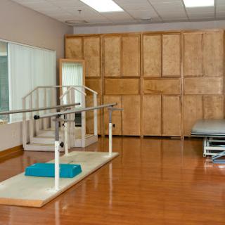 A spacious physical therapy room equipped with parallel bars and exercise mats for rehabilitation.