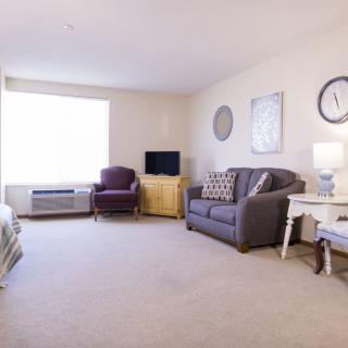 A cozy living room with a sofa, chair, and television.
