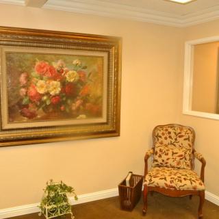A cozy room with a floral painting and an ornate chair.