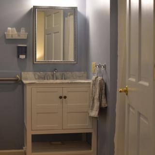 A cozy bathroom with a vanity, mirror, and blue walls.