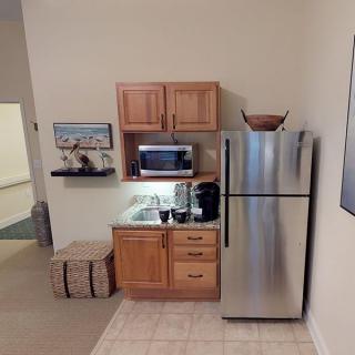A small kitchen area with a mini-fridge, microwave, and wooden cabinets.