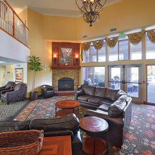 A spacious hotel lobby with comfortable seating, a central fireplace, and large windows.
