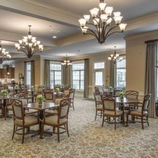 A spacious and elegantly decorated dining room with multiple tables and chairs, adorned with stylish chandeliers.