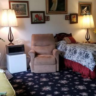 Cozy living space with an armchair, two lamps, and a bed surrounded by wall art.