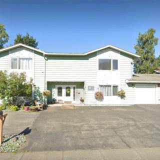 A suburban two-story house with a driveway and surrounding greenery.